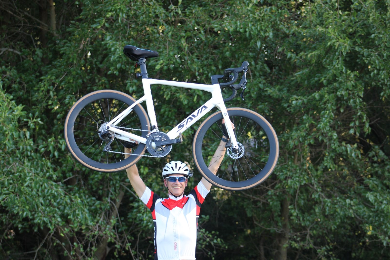 Wayne Kennedy holding his SAVA carbon road bike overhead after a ride